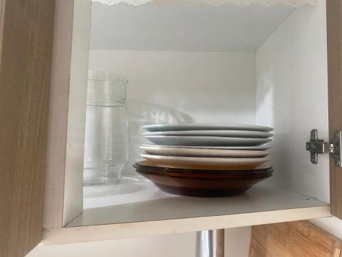 a cabinet with a stack of plates and a glass at 08 - Apê próximo ao Metrô e Centro com Wi-Fi e Ar condionado in São Leopoldo