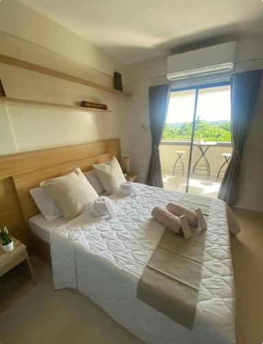 a bedroom with a large white bed with a window at The Coastal Luxe Suite in Samal