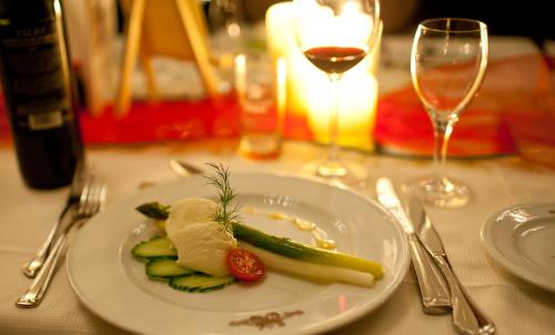 a plate with vegetables on a table with wine glasses at Klosterbräuhaus Ursberg in Ursberg