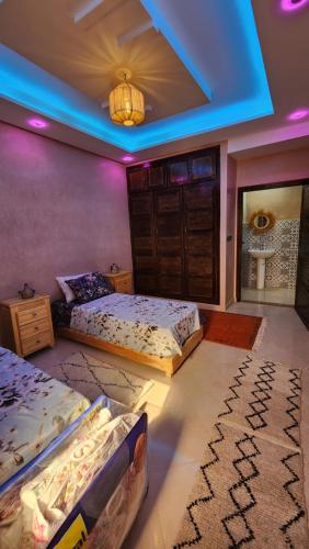 a bedroom with three beds and a blue light at VibeLine Surf Camp in Tamraght Ouzdar