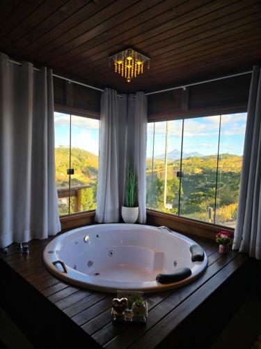 a large bath tub in a room with windows at Chales Vidal in Venda Nova do Imigrante