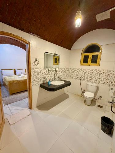 a bathroom with a sink and a toilet and a bed at Al-Sultan Hotel in Al Aqālitah