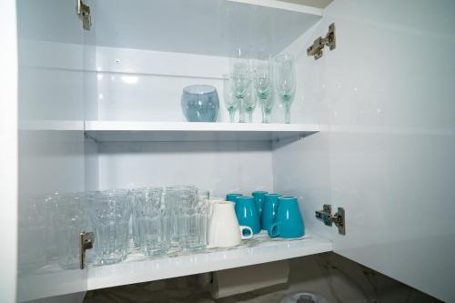 a shelf with glasses and bottles on it at Amplio, cómodo y cerca Del Mar in Porlamar
