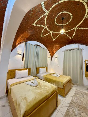 two beds in a room with a ceiling with a painting at Al-Sultan Hotel in Al Aqālitah