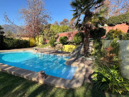 a swimming pool in a yard with a palm tree at Casa Super Vista a los Andes in Santiago