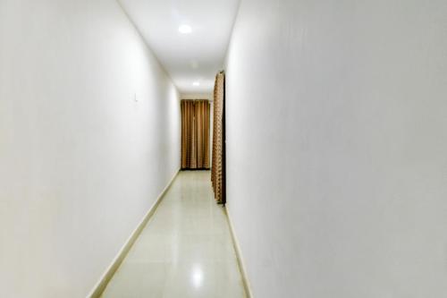an empty corridor with white walls and a door at Hotel O Ksp Lodge in Neyveli