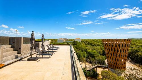 a patio with chairs and umbrellas on top of a building at Mayan View Walk to Beach & Tulum Ruins in Tulum