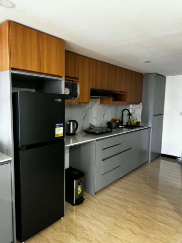 a kitchen with a black refrigerator and wooden cabinets at Luxury Loft at Crown Regency in Cebu City