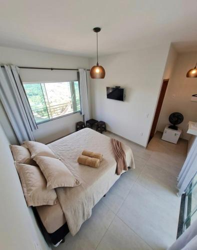 a bedroom with a bed and a large window at Chalet Alta Vista Acuruí in Itabirito