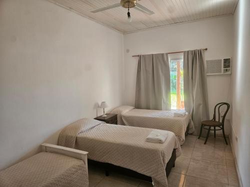 a room with three beds and a window at El Ñangapiri in Mercedes