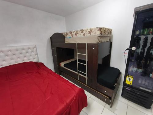 a small room with a bunk bed and a red bedspread at Quincho Ruben in La Rioja