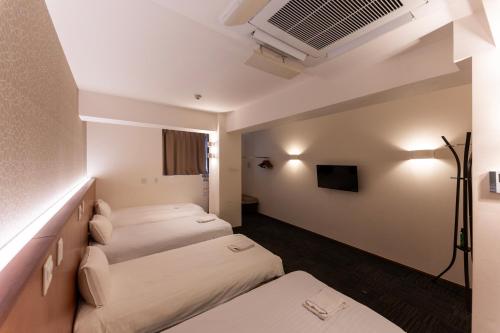 a hotel room with two beds and a tv at COCOSHUKU Tokyo Nakano in Tokyo