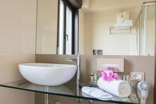 a bathroom with a glass counter with a sink and a mirror at Villa Morgana Resort and Spa in Torre Faro
