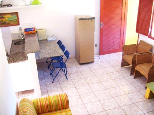 a room with a kitchen with a refrigerator and chairs at Pousada Recanto do Sossego in Itamaracá