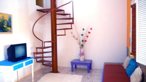 a living room with a spiral staircase and a tv at Pousada Recanto do Sossego in Itamaracá