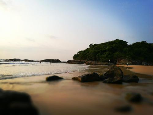a beach with some rocks in the water at Guesthouse Dilush in Beruwala
