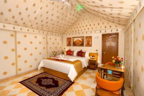 a bedroom with a bed and a table and a chair at Desert Popular Resort & Camp in Jaisalmer