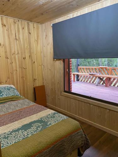a bedroom with a large window with a view of a deck at Casa Salto Pichi Ignao in Lago Ranco