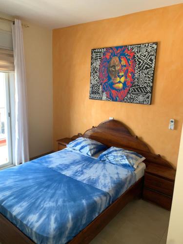 a bedroom with a bed with a painting on the wall at Immeuble carrefour 2 in Ngaparou