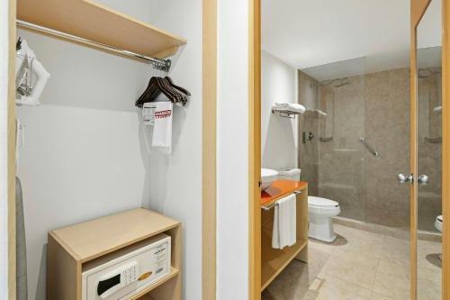 a bathroom with a shower and a toilet and a microwave at Fiesta Inn Express Perinorte in Mexico City