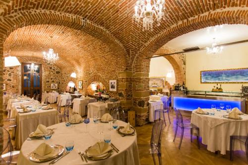 um restaurante com mesas e cadeiras brancas e uma parede de tijolos em Mariano IV Palace Hotel em Oristano