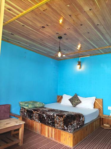 a bed in a room with a blue wall at Pulga Inn in Kalgha