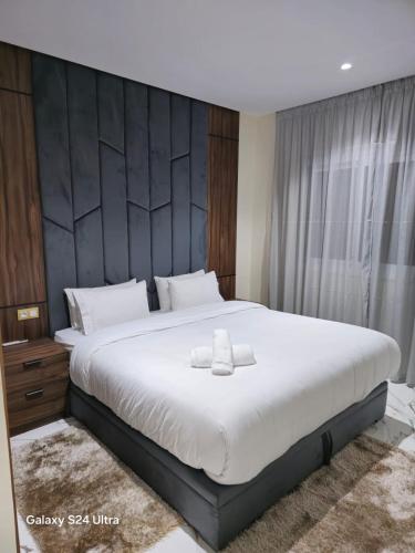 a bedroom with a large white bed with a black headboard at Appart Hôtel Stade Tanger in Tangier