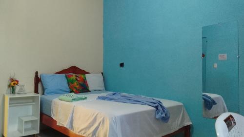 a bedroom with a bed with a blue wall at Hostal La GRAN Familia in Manta