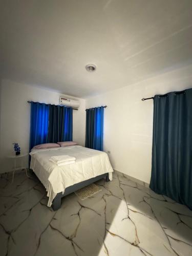 a bedroom with a bed and blue curtains at Apartamentos SCARLEM in Higuey