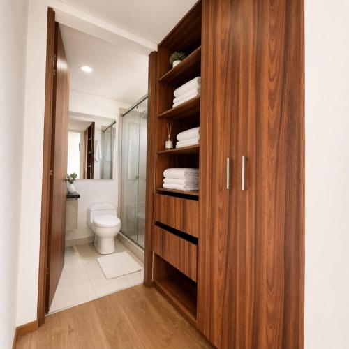 a bathroom with a toilet and a wooden cabinet at Edificio Urban in Cajicá