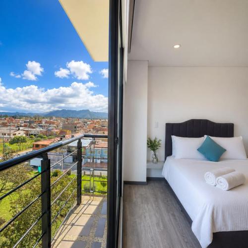 a bedroom with a bed and a balcony with a view at Edificio Urban in Cajicá