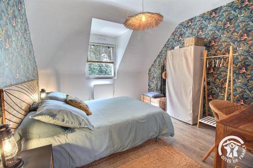 a bedroom with a bed and a wall covered in wallpaper at La maison verte in Ploeuc