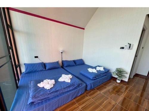 a bedroom with two blue beds with towels on them at ปลายเขื่อนแคมป์ปิ้ง บ้านแฟมรี่ in Sirindhorn