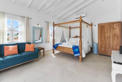 a bedroom with a canopy bed and a blue couch at Beach Walk Residences in Palm-Eagle Beach