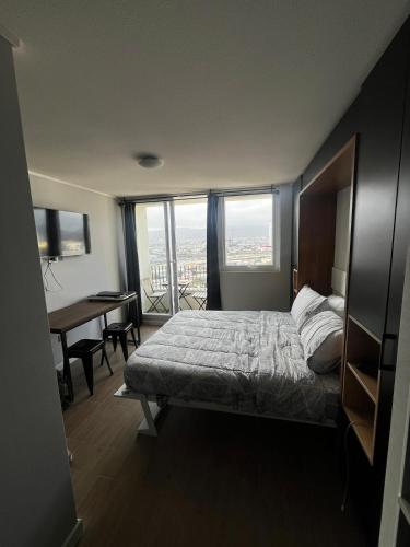 a bedroom with a bed and a desk and windows at Despierta con una vista impecable cada mañana in Coquimbo