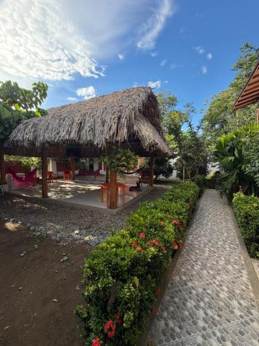 a hut with a straw roof and some flowers at Mi Ranchito Capurganá in Capurganá