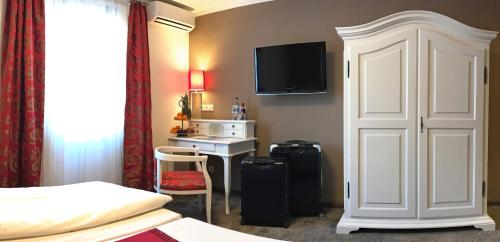 a hotel room with a bed and a desk with a television at Boutiquehotel Goldhahn Bio Sport & Wellness in Aalen