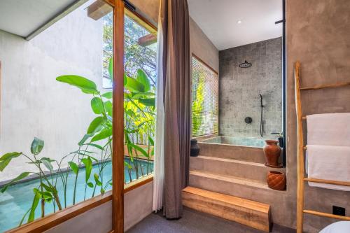 a bathroom with a bath tub and a window at Villa Dinova in Uluwatu