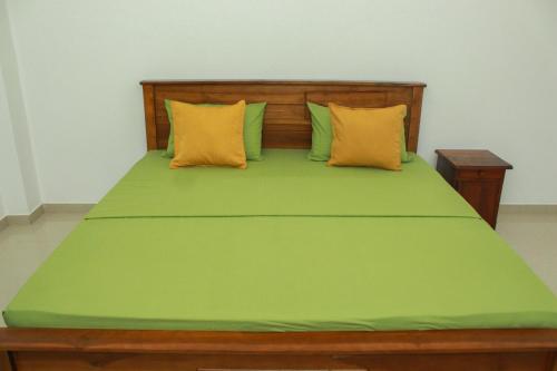 a bed with green sheets and yellow pillows at Villa Deniyaya in Deniyaya