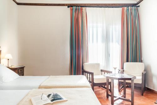 a hotel room with two beds and a table and chairs at Parador de Manzanares in Manzanares