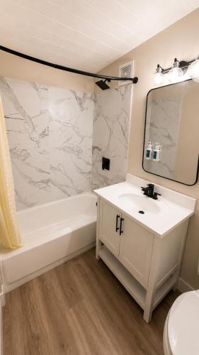a bathroom with a sink and a tub and a mirror at Anchor Bay Inn near Winchester Bay in Reedsport