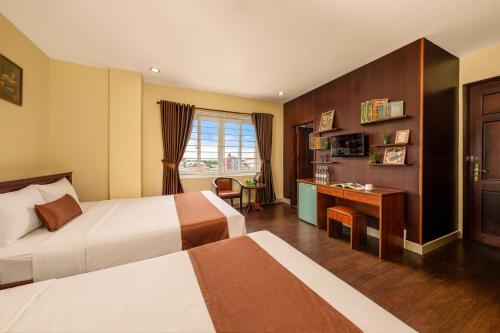 a hotel room with two beds and a desk at Vina Boutique Hotel in Hue