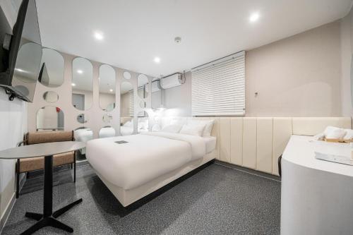 a white bedroom with a large white bed and a desk at 구리 호텔 옐로 in Guri
