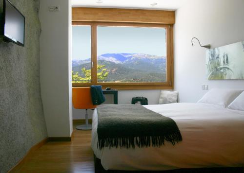 a bedroom with a bed and a large window at Posada del Agua in El Barraco