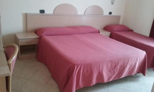 two beds in a room with pink sheets on them at Hotel Europa in San Bartolomeo al Mare