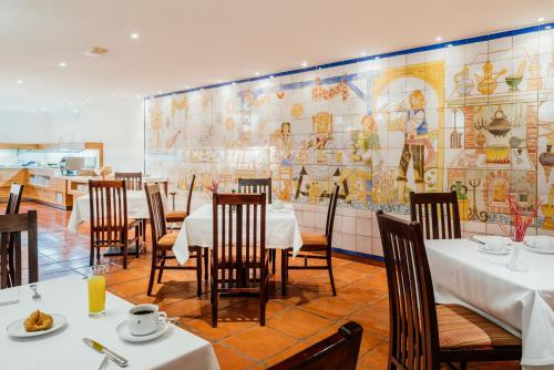 a restaurant with white tables and chairs and a mural at Parador de Manzanares in Manzanares