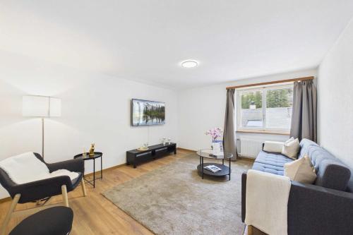 a living room with a blue couch and two chairs at Alpine Apartment near Saas-Fee for 4 in Saas-Almagell