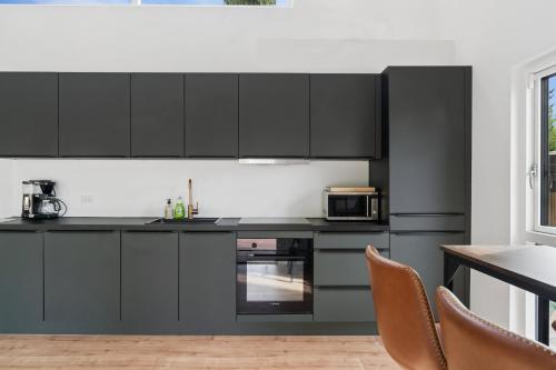 a kitchen with black cabinets and a table and chairs at Newly Renovated Cottage With Sauna in Melby