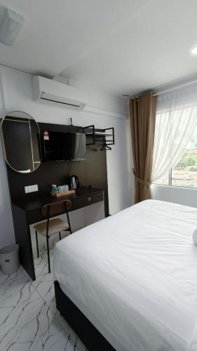 a bedroom with a bed and a desk and a television at Dwan Hotel in Kota Bharu