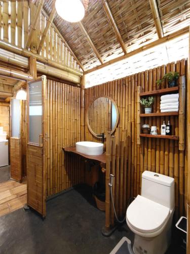a bathroom with a toilet and a sink and a mirror at สวนเกษตรรักษ์ไผ่ Bamboo Conservation Farm in Surin